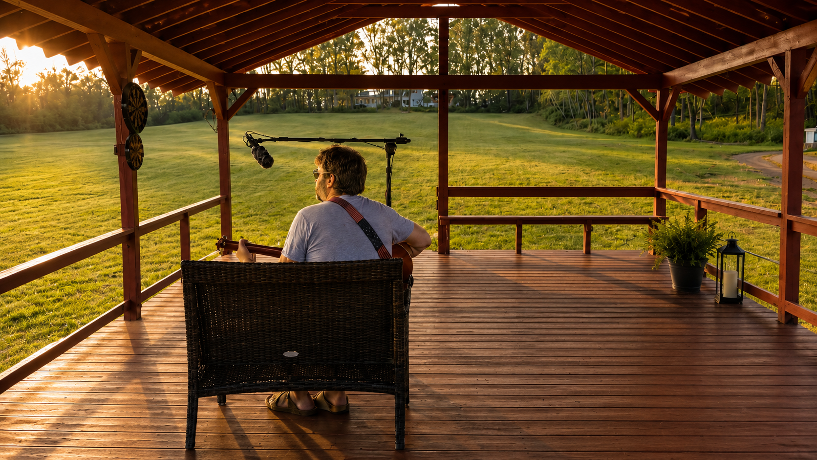 Musician playing guitar on the covered field stage at golden hour