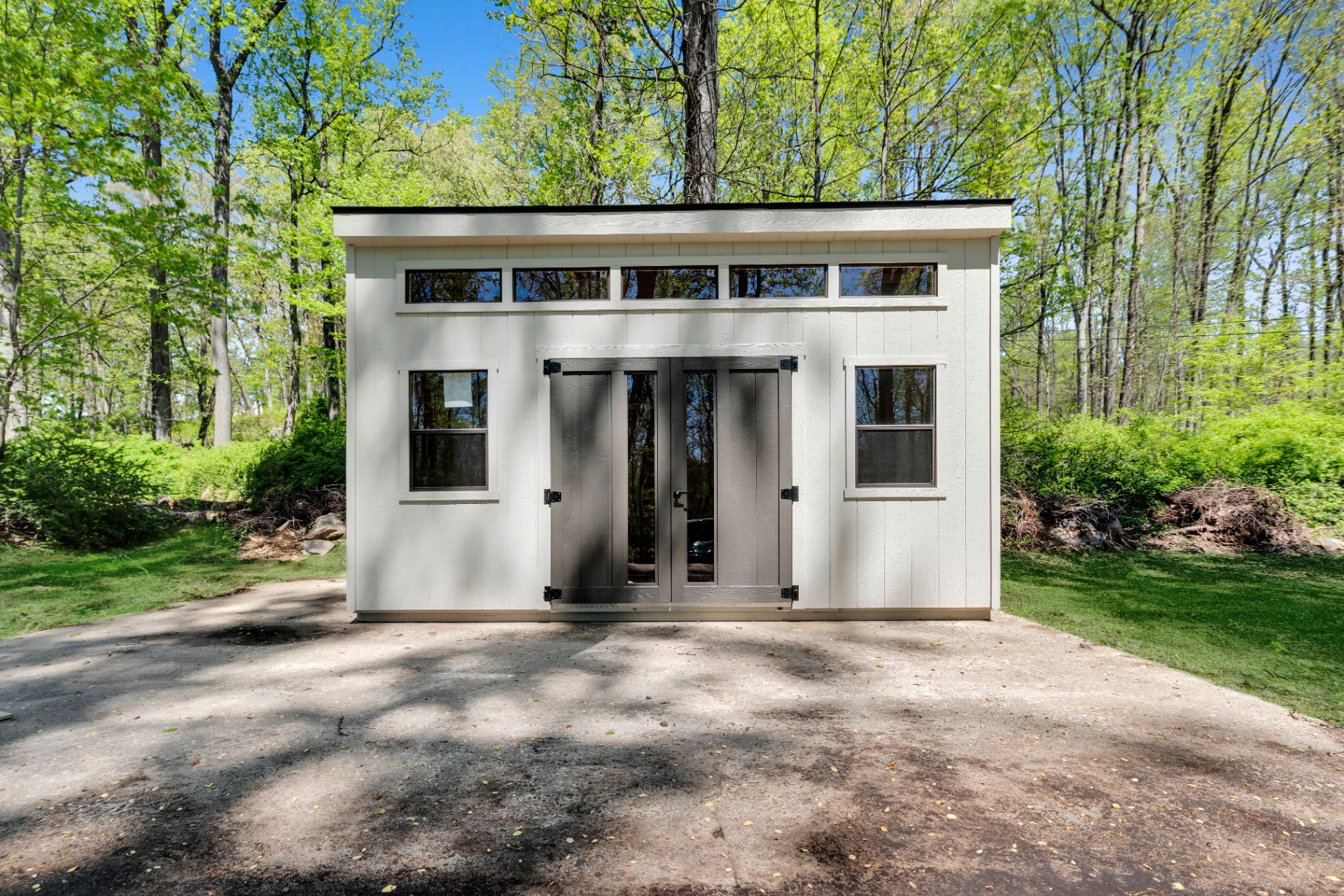 White studio shed at the edge of the woods